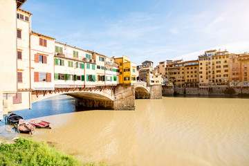 Obraz premium Cityscape view on famous Ponte Vecchio bridge with boats on the river in Florence
