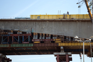 One worker in workwear standing high on a bridge processing construction work