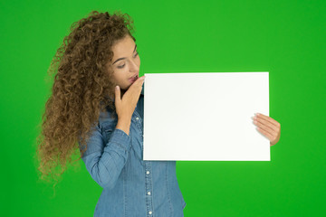 The young woman show empty sheet of paper the green background