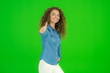 The young woman stand and show thumb up on the green background