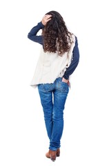 back view of standing young beautiful woman Long-haired girl with curly hair thoughtfully scratching his head.