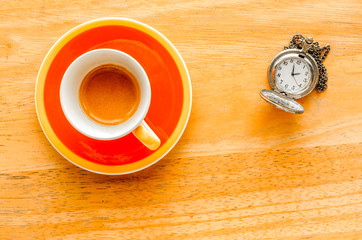 Orange cup of espresso with pocket watch