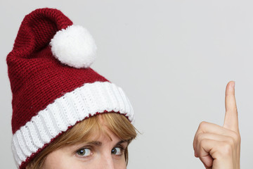 Girl in a cap of Santa Claus showing thumb up