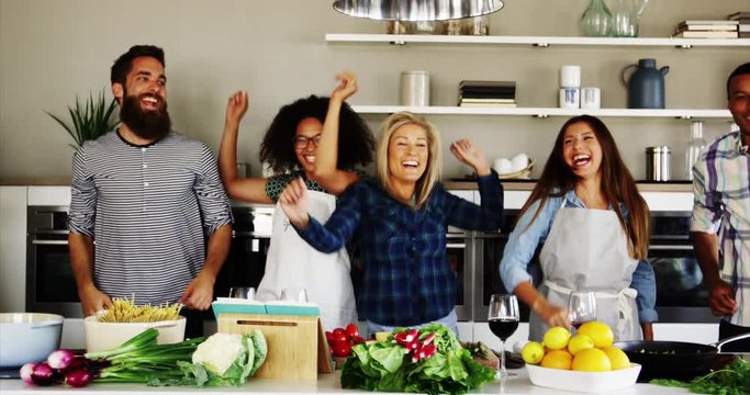 Friends Jumping up and dancing in kitchen while laughing and having fun