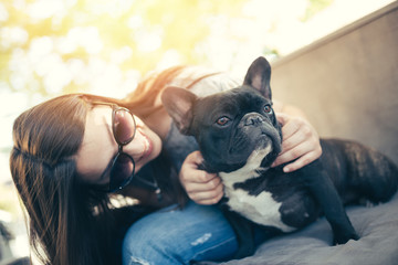 Cute teenager girl enjoying outdoors in cafe bar together with her adorable French bulldog puppy....