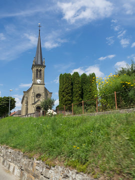 Vista de una iglesia en forma de l&aacute;piz con una punta aguda al cielo azul con c&eacute;sped verde en primer plano en Haute Ville pueblo de Gruy&egrave;res, Suiza viajando en verano de 2016