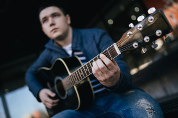 Young teenager musician urban outdoor portrait. Boy playing guitar on street.