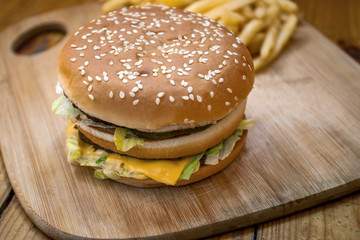 Fast food set big hamburger and french fries on wood background