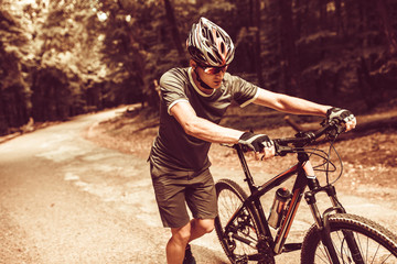 Young mountain biker pushing his bike uphill.