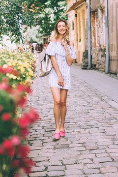 beautiful young blonde woman walking on the street and talking on a cell phone,the girl laughs and smiles,the perfect photo for mobile advertising travel,shopping for magazines,photo -style lifestyle