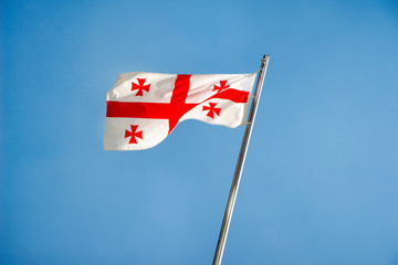 Georgia flag fluttering on a metal flagpole 