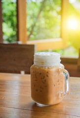 Milk tea with ice in Glass handle on wooden table.