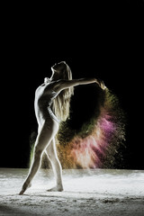 Obraz na płótnie Canvas Finale - Young dancer traces patterns through a cloud of powder as she dances against a dark background