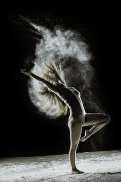 Celebrate - Young dancer traces patterns through a cloud of powder as she dances against a dark background