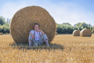 Naklejka na ściany i meble Junger Mann entspannt im Feld nach der Ernte