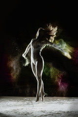 Obraz na płótnie Canvas Ascend - Young dancer traces patterns through a cloud of powder as she dances against a dark background