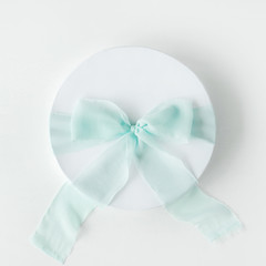 Naklejka premium white gift cardboard box with blue bow on white background. flat lat, top view