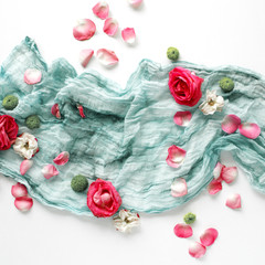 decorated composition with red roses, pink petals and blue textile on white background. Flat lay, top view