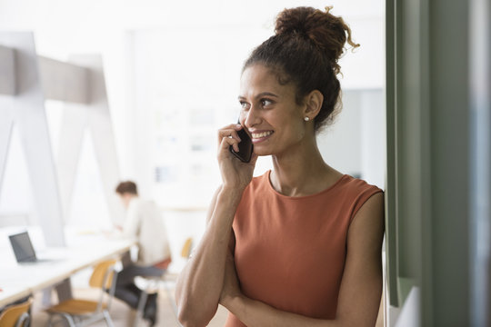 Smiling woman in office on cell phone