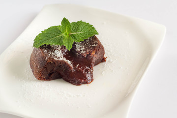 Molten cake on white plate with mint leaves