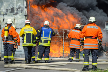 Fototapeta premium Feuerwehrmänner vor brennendem Gebäude