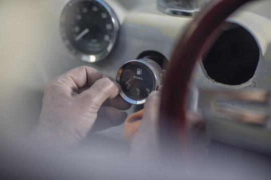 Senior man adjusting fuel gauge of a car