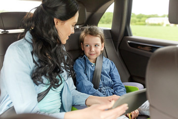 happy family with tablet pc driving in car