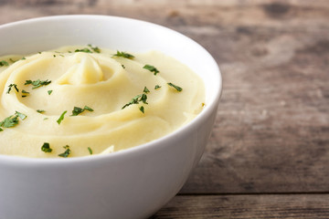 Mashed potato in white bowl on wooden table

