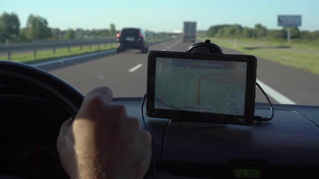 GPS navigation in car with man driving 4K. Close up on navigation screen showing road to follow. Smartphone navigation device.