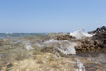 Sea wave splashing over the shore rocks with a high sea spray