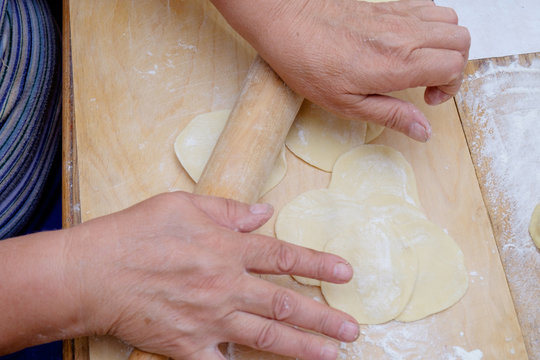 Dough being flattened on a wooden cutting wooden board