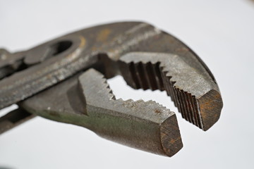 Macro detail of an old rusty pliers with its adjustable cogged head on the isolated background 