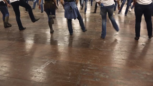 Legs of western dancers dancing a choreography at a country festival, wearing cowboy boots, jeans and USA flag. Learning line dance. Music, traditions and fun