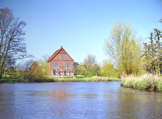 House at a riverside. Farm house in the sun. Sunny day at a river in North Germany.