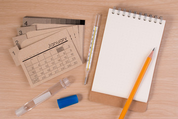 Hospital agendar on doctor table. Calendar, thermometer and pencil on wooden table.