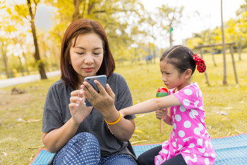 Mother playing smart phone with careless her daughter