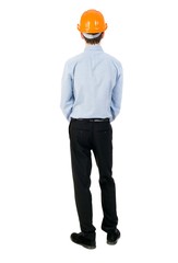 Backview of an engineer in construction helmet stands. Isolated over white background. The curly-haired businessman in light shirt and hat thoughtfully looks ahead.