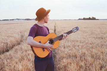 young man playing guitar in the field at sunset, romantic love song