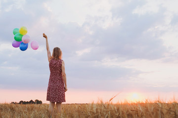 hope concept, emotions and feelings, woman with colourful balloons in the field, background