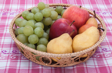 Naklejka na ściany i meble wicker baskets with fruit closeup on a checkered tablecloth