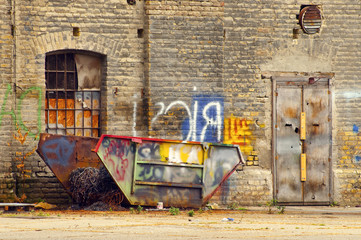 Garbage container in front of abandoned factory building