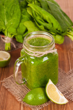 Jar mugs filled with green fresh organic spinach and lime lemon smoothie. Detox concept.