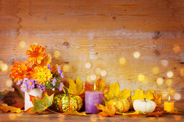 Herbst  -  Dekoration mit Blumen, Kerzen und Kürbis vor Holz