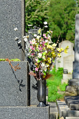 Fototapeta na wymiar Kunstblumen in einer Vase am Grabstein