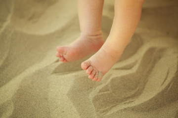 Newborn baby feet playing in the sand