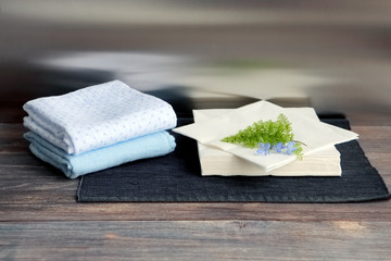Cotton and paper tussues on a wooden table. Composition with slate board, wooden table, fern leaf, reflections.