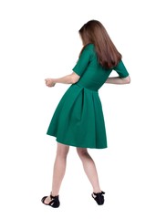 back view of standing girl pulling a rope from the top or cling to something. backside view of person. Isolated over white background. The slender brunette in a green short dress pulls the rope.