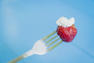 Strawberry with cream on fork