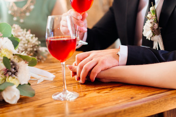 Man and woman hold their hands on wooden table where stand wineg