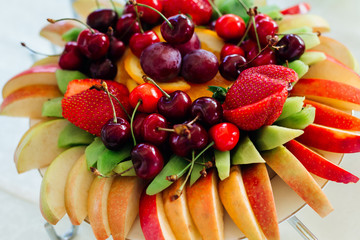 Sliced apples, kiwi, strawberries and cherries lies served on th